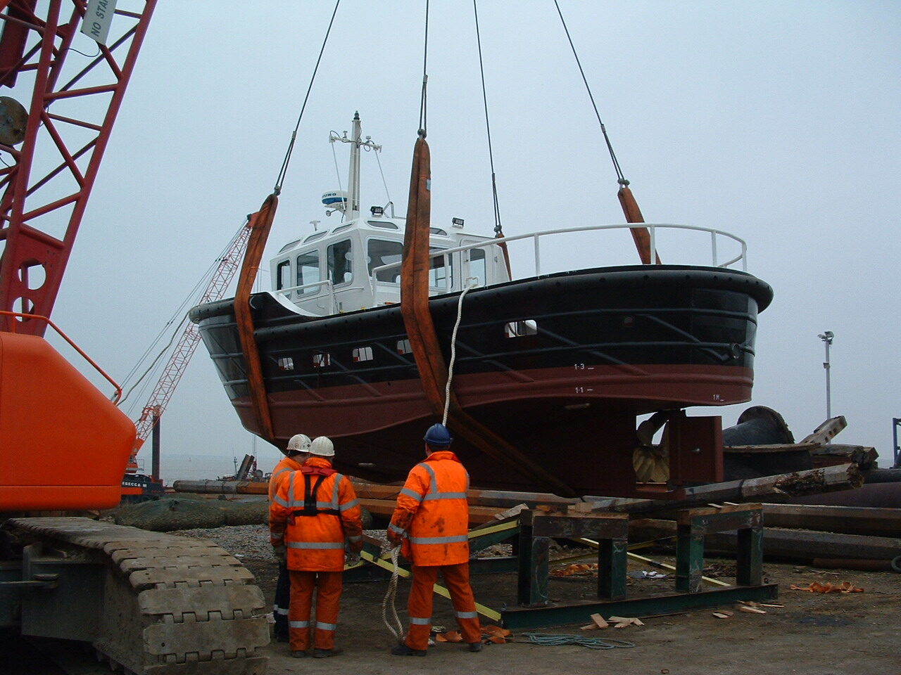 Crew supervising a workboat lift onto the cradle